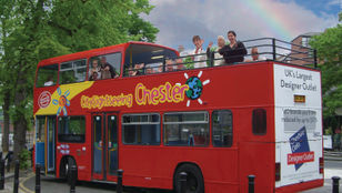 City Sightseeing Chester: Hop-On, Hop-Off bus filled with enthusiastic passengers waving, ready to embark on an exciting city exploration.
